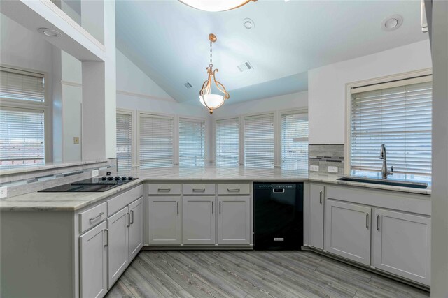 kitchen featuring kitchen peninsula, tasteful backsplash, vaulted ceiling, sink, and black appliances