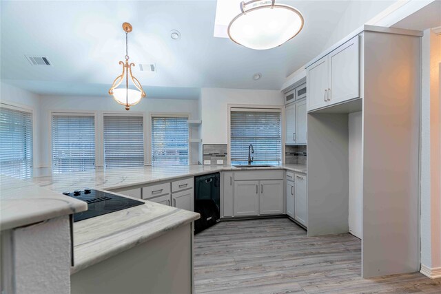 kitchen featuring black appliances, backsplash, pendant lighting, and light wood-type flooring