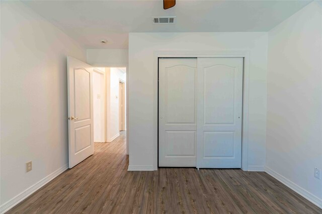 unfurnished bedroom with a closet, dark hardwood / wood-style flooring, and ceiling fan