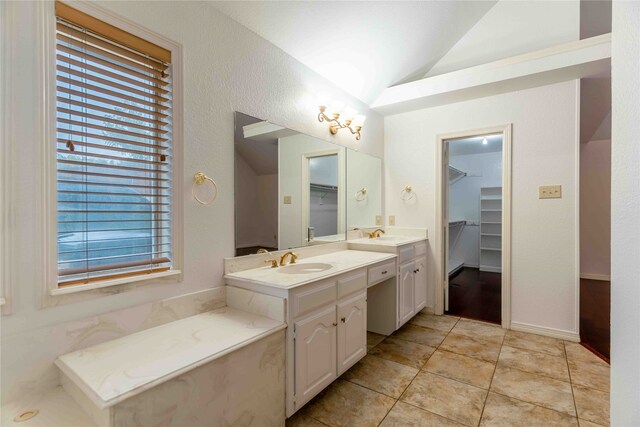 bathroom with tile patterned flooring, vanity, and vaulted ceiling