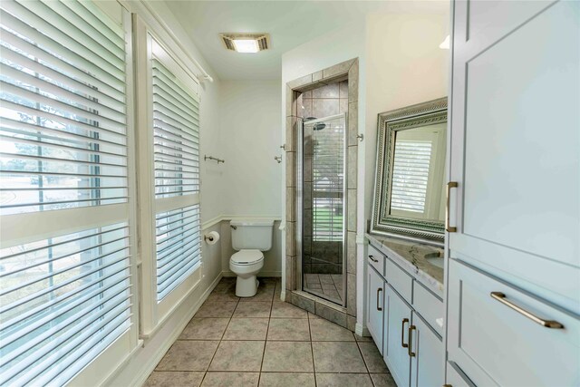 bathroom featuring tile patterned floors, vanity, a shower with shower door, and toilet