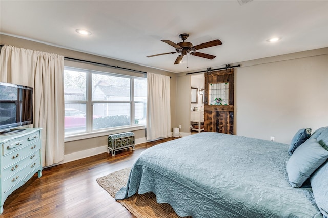 bedroom with a barn door, ceiling fan, and dark hardwood / wood-style floors