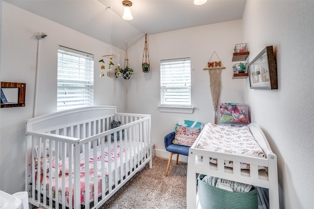 carpeted bedroom with multiple windows, vaulted ceiling, and a nursery area