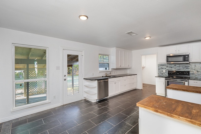 kitchen with white cabinets, stainless steel appliances, tasteful backsplash, and sink