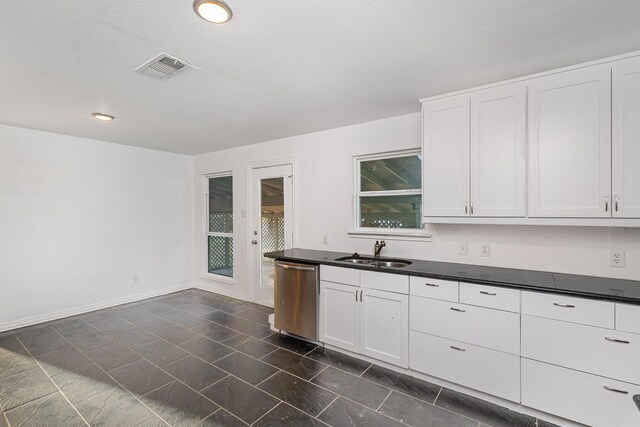 kitchen with white cabinets, dishwasher, sink, and a textured ceiling