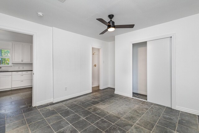 unfurnished bedroom featuring a closet, ensuite bath, and ceiling fan