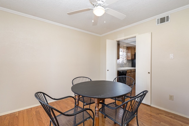 dining space with ceiling fan, sink, crown molding, a textured ceiling, and light wood-type flooring