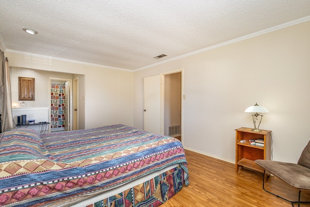 bedroom featuring a textured ceiling, light hardwood / wood-style floors, and crown molding