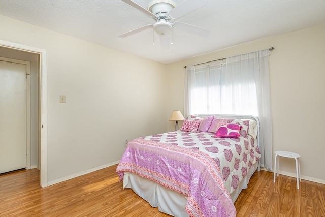 bedroom with ceiling fan, a textured ceiling, and hardwood / wood-style flooring