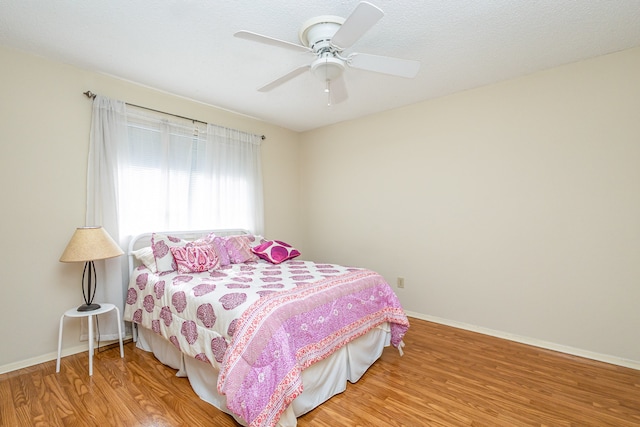 bedroom featuring ceiling fan, wood-type flooring, and a textured ceiling