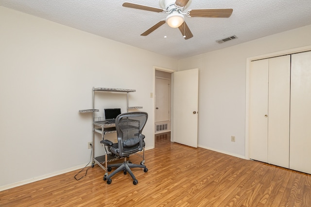 home office with ceiling fan, a textured ceiling, and light hardwood / wood-style flooring