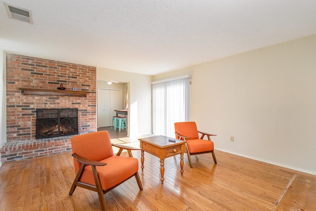 living area featuring a fireplace, a textured ceiling, and light wood-type flooring