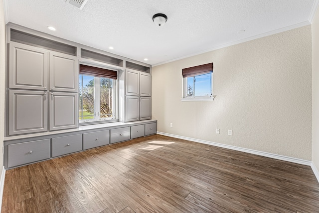 unfurnished bedroom featuring multiple windows, dark wood-type flooring, a textured ceiling, and crown molding