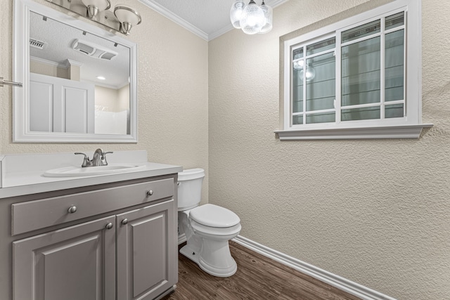 bathroom featuring hardwood / wood-style floors, vanity, toilet, ornamental molding, and a textured ceiling