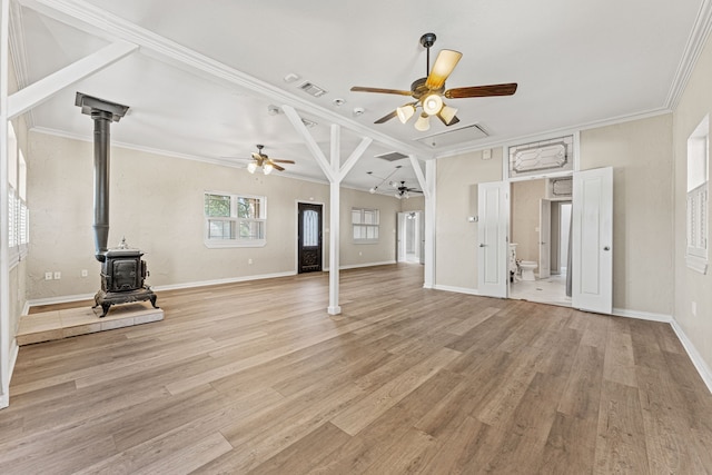 unfurnished living room featuring light hardwood / wood-style flooring, a wood stove, ceiling fan, and ornamental molding