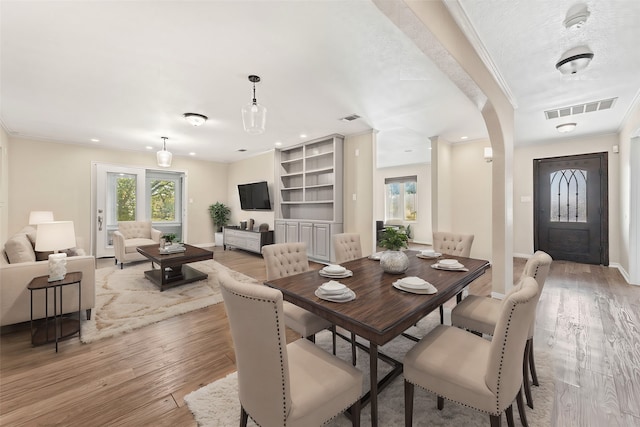 dining area with a textured ceiling, light hardwood / wood-style floors, and crown molding