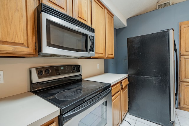 kitchen with light tile patterned floors, stainless steel appliances, and a textured ceiling