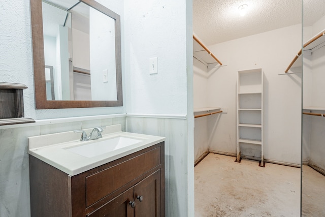 bathroom with concrete flooring, vanity, and a textured ceiling