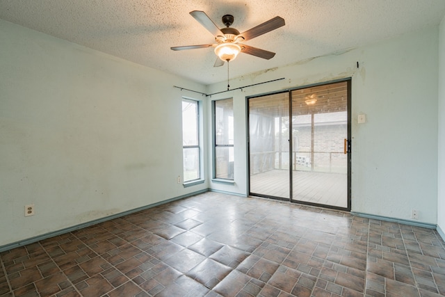 empty room with ceiling fan and a textured ceiling