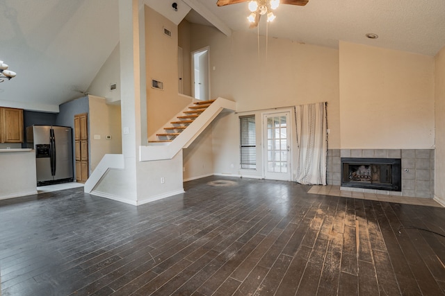 unfurnished living room with dark hardwood / wood-style flooring, a tile fireplace, a textured ceiling, and high vaulted ceiling