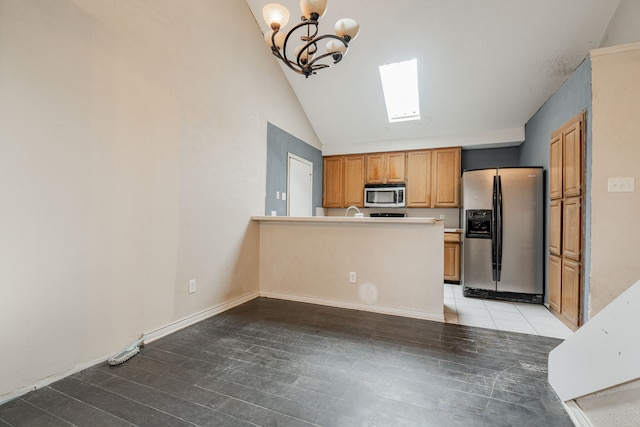 kitchen with lofted ceiling with skylight, an inviting chandelier, stainless steel appliances, and light wood-type flooring