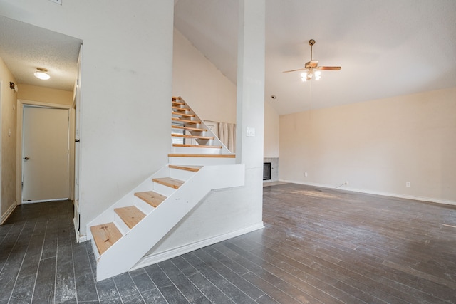 staircase with wood-type flooring, a textured ceiling, high vaulted ceiling, and ceiling fan