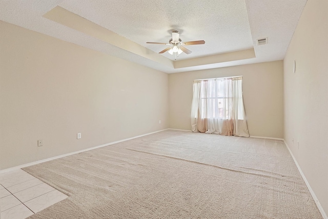 carpeted spare room featuring a textured ceiling, a raised ceiling, and ceiling fan