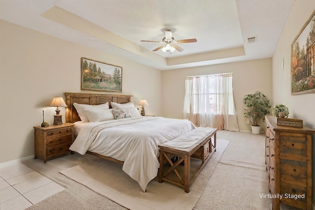 bedroom with ceiling fan, light tile patterned flooring, and a raised ceiling