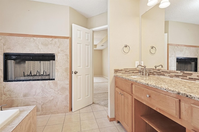 bathroom featuring tile patterned floors, a textured ceiling, a tiled fireplace, vanity, and tile walls