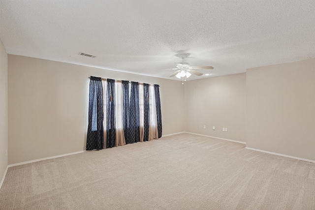 empty room with light carpet, a textured ceiling, and ceiling fan