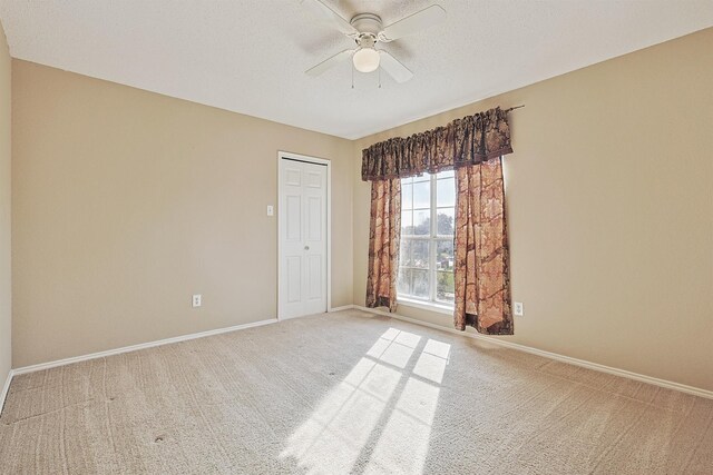 carpeted spare room featuring ceiling fan