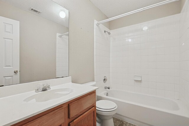 full bathroom featuring tiled shower / bath, vanity, a textured ceiling, and toilet