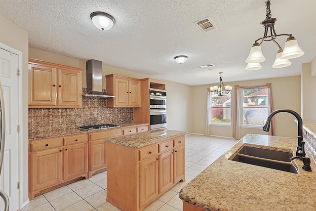 kitchen featuring a center island, wall chimney exhaust hood, sink, a chandelier, and pendant lighting