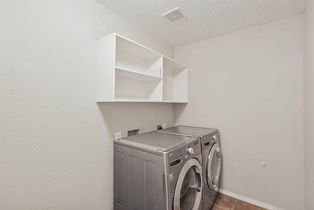 clothes washing area featuring washing machine and dryer and a textured ceiling