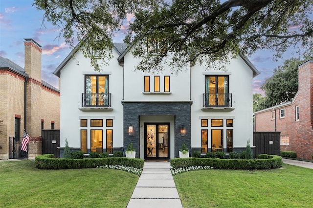 view of front facade featuring a lawn and a balcony