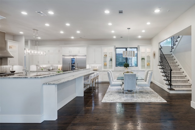 kitchen featuring pendant lighting, a kitchen breakfast bar, stainless steel built in fridge, and white cabinets