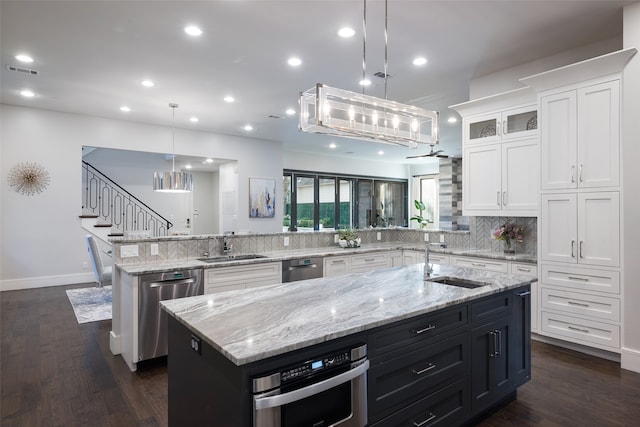 kitchen featuring sink, kitchen peninsula, a spacious island, decorative light fixtures, and white cabinets