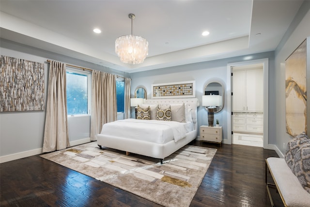 bedroom with a raised ceiling, dark hardwood / wood-style floors, and an inviting chandelier