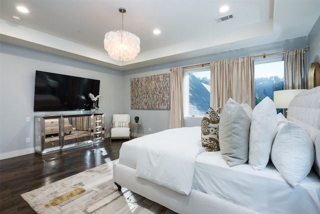 bedroom with hardwood / wood-style floors, a notable chandelier, and a raised ceiling