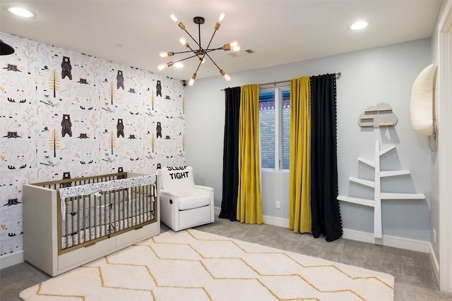 carpeted bedroom featuring a crib and a notable chandelier