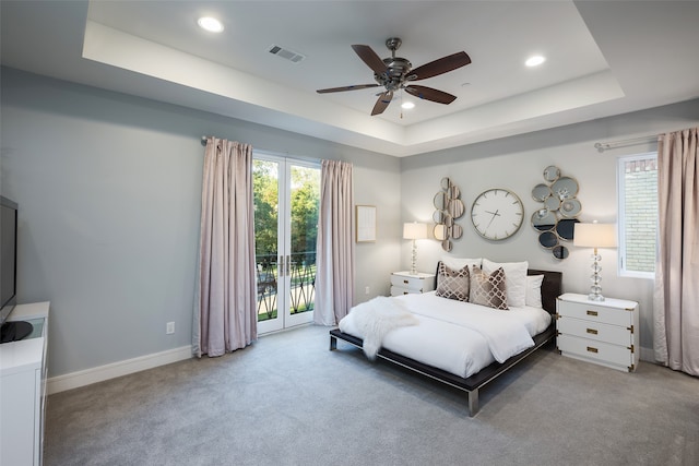 bedroom with access to exterior, light carpet, a raised ceiling, and ceiling fan