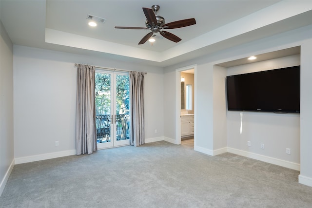 unfurnished living room with light carpet, a tray ceiling, and ceiling fan