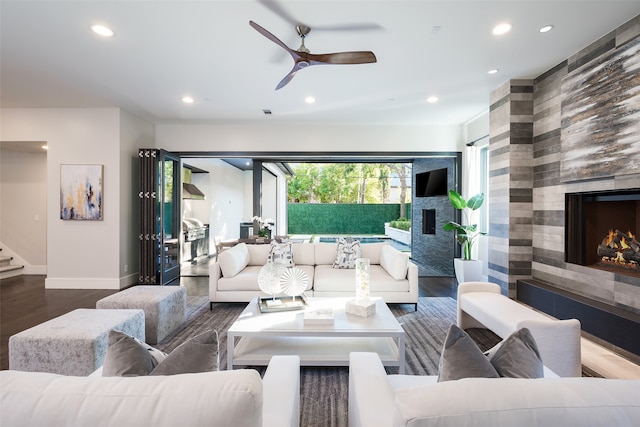 living room featuring a tiled fireplace, ceiling fan, and wood-type flooring