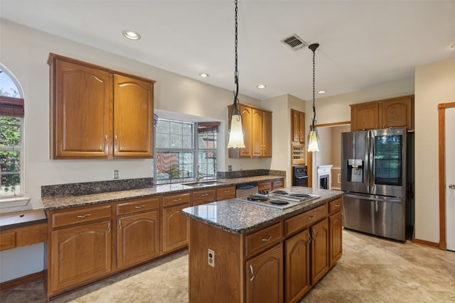 kitchen with decorative light fixtures, a center island, stainless steel appliances, and dark stone countertops