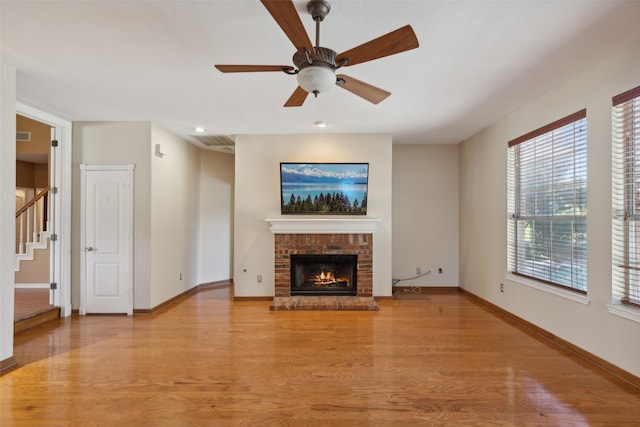 unfurnished living room with ceiling fan, light wood-type flooring, and a brick fireplace