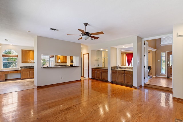 unfurnished living room with light hardwood / wood-style flooring, ceiling fan, and a healthy amount of sunlight