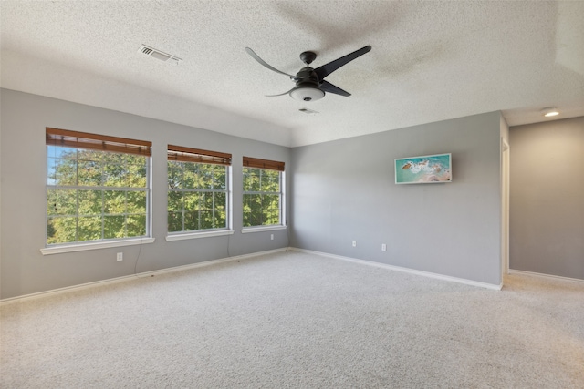 carpeted spare room with ceiling fan, a healthy amount of sunlight, and a textured ceiling