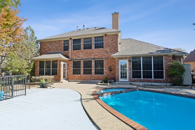 back of property featuring a pool with hot tub