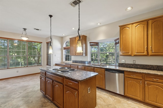 kitchen with a center island, dark stone counters, sink, decorative light fixtures, and stainless steel appliances