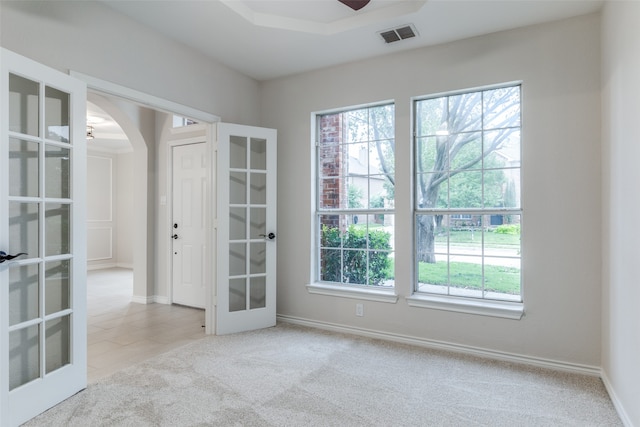 spare room with light carpet, french doors, and ceiling fan